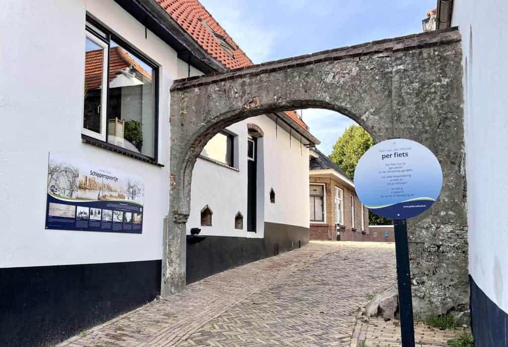 Oude poort op 't Gelders Eiland met informatiebord en smalle straat.
