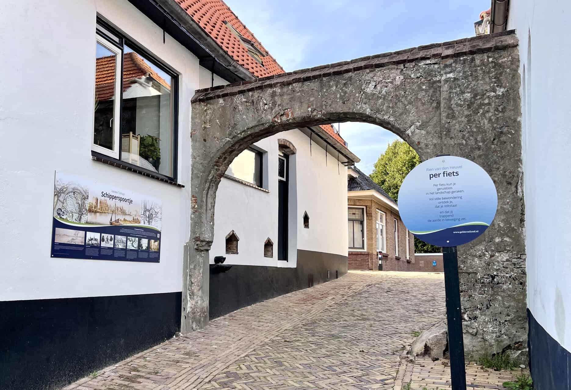 Oude poort op 't Gelders Eiland met informatiebord en smalle straat.