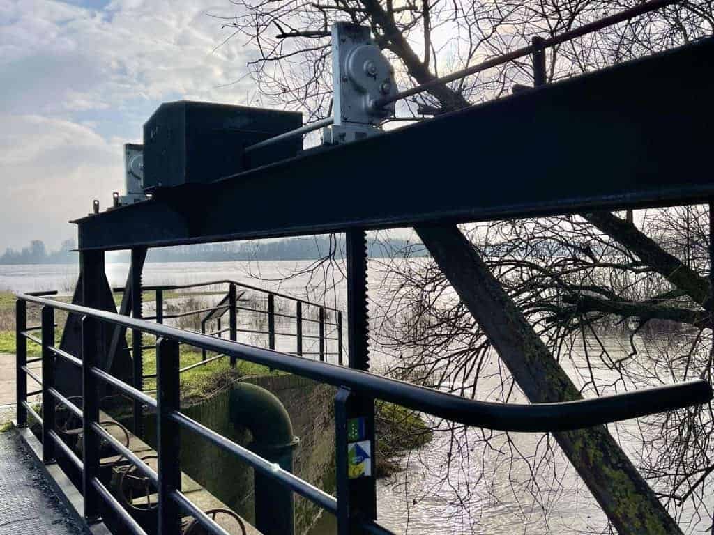 Brug over de rivier op 't Gelders Eiland met uitzicht op water en bomen.