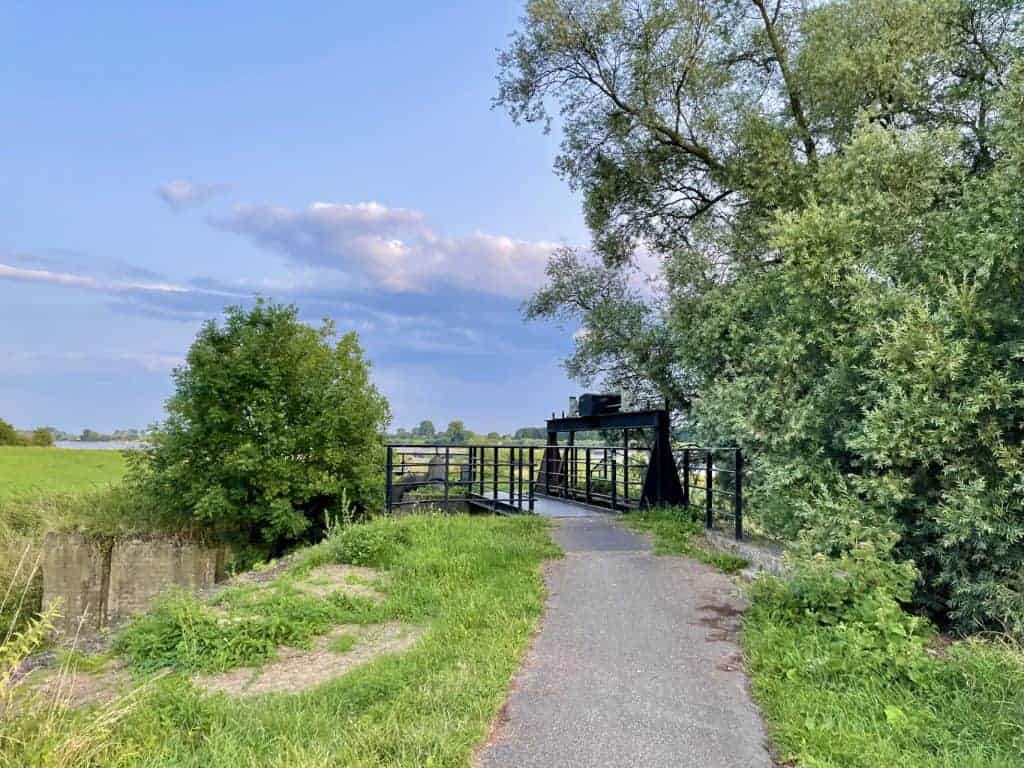 Pittoreske brug op 't Gelders Eiland omgeven door groene bomen en weilanden.