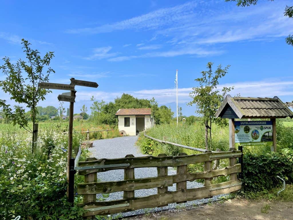 Rustige wandelroute met informatiebord en kleine huisjes op 't Gelders Eiland.