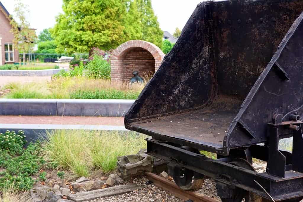 Historische mijnwagen op 't Gelders Eiland met groene omgeving en oude bakstenen boog.