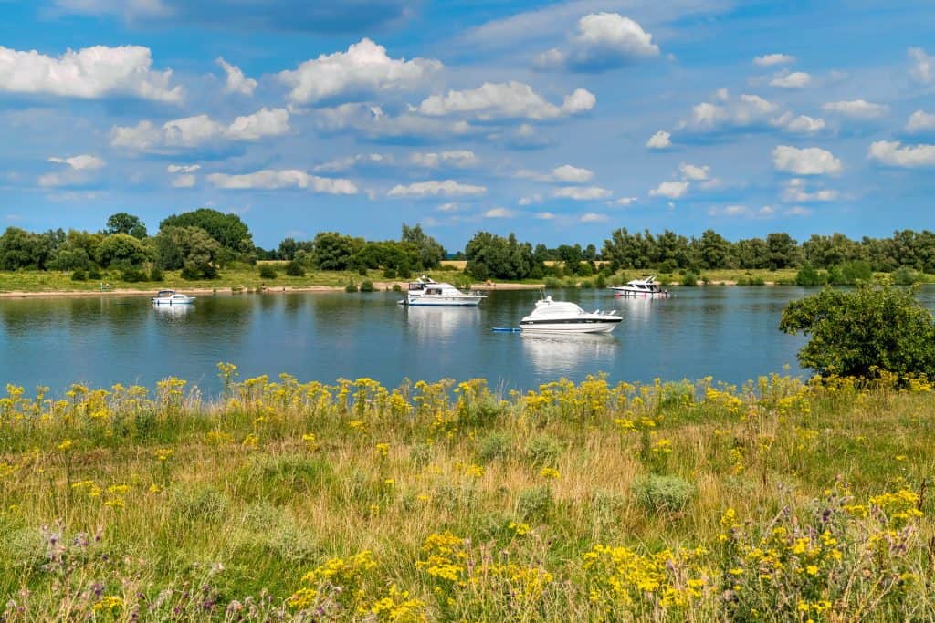 Uitzicht op de rivier met boten en groene oevers onder een blauwe hemel.