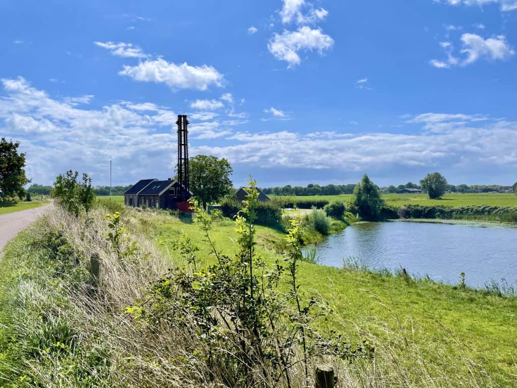 Rustige rivier met groene oevers en een oude molen op de achtergrond.