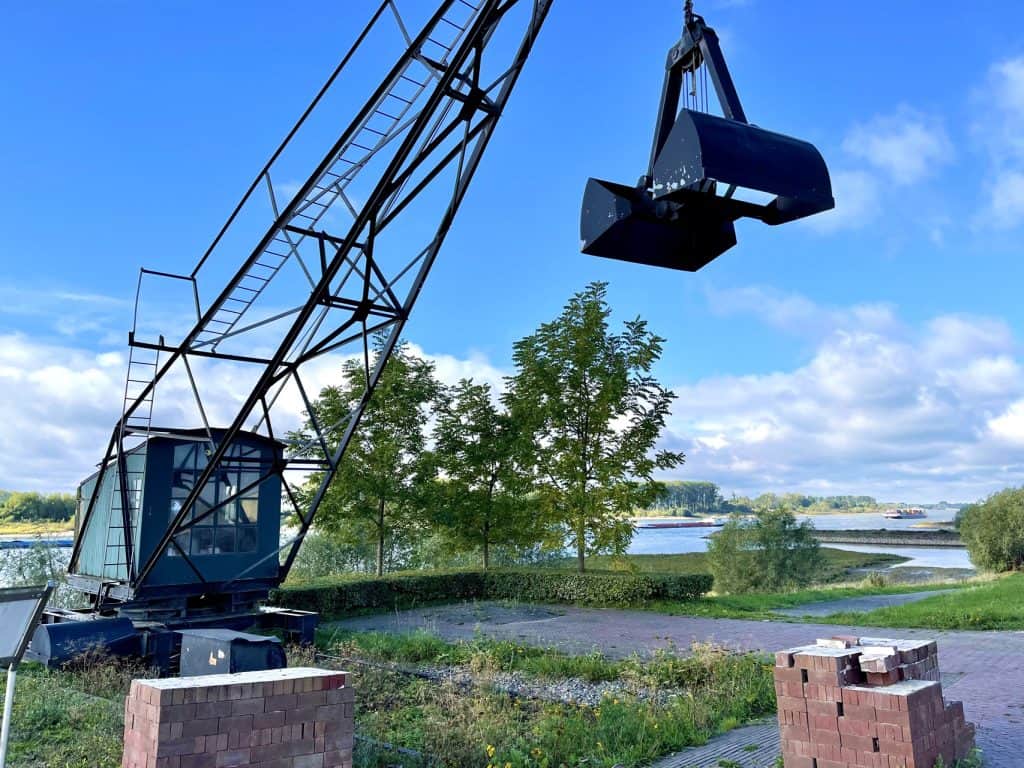 Oude industriële kraan met uitzicht op rivier en landschap.