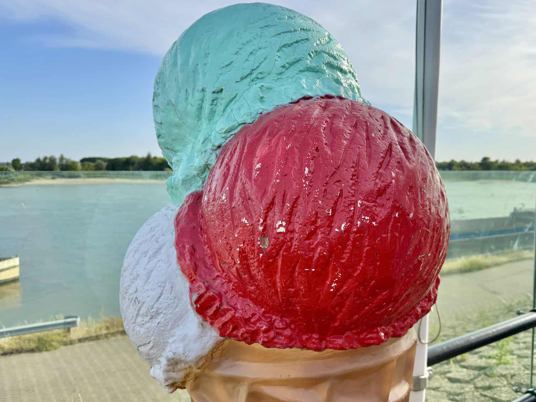 Drie bolletjes ijs op een ijsje met uitzicht op het water.