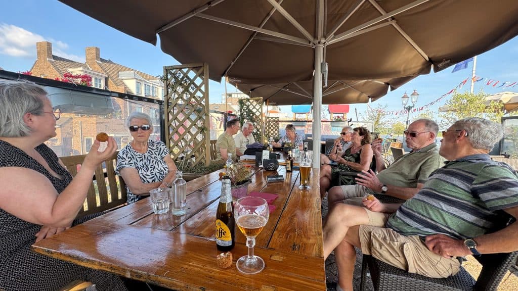 Gezellig terras met mensen onder parasol op 't Gelders Eiland.