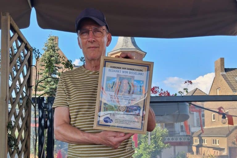 Man houdt een certificaat vast onder een parasol op 't Gelders Eiland.