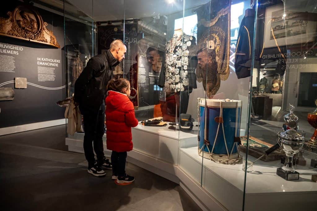 Gezinnen bekijken historische artefacten in het Liemers Museum.