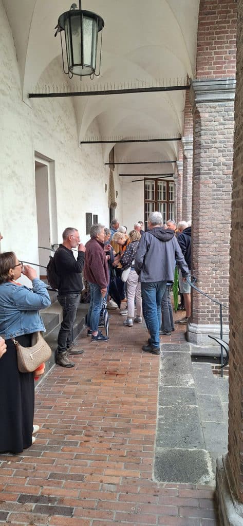Groep mensen wacht onder een overkapping op 't Gelders Eiland.