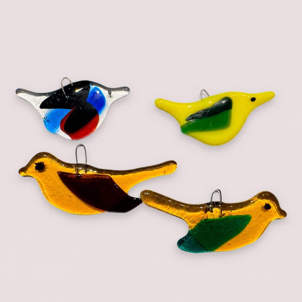 Kleurrijke glazen vogelversieringen op wit achtergrond.