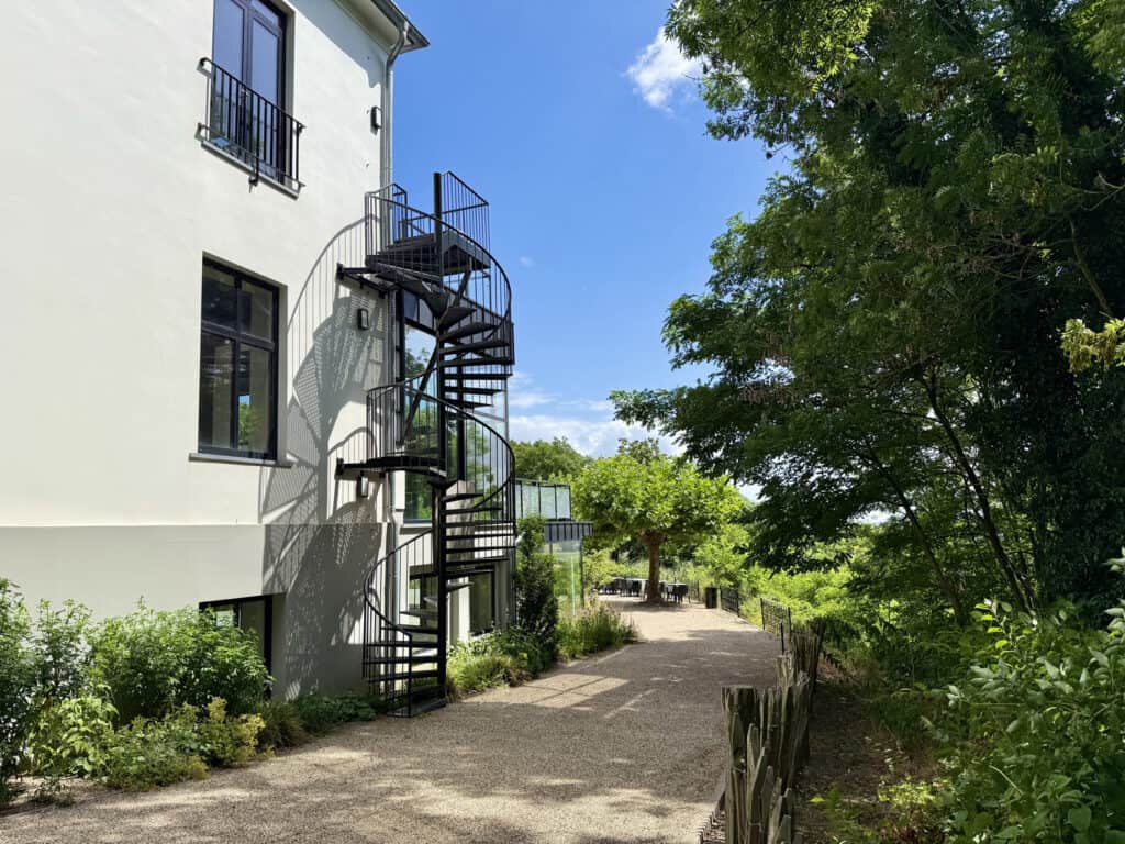 Moderne witte woning met zwarte buitentrap en groene tuin op 't Gelders Eiland.