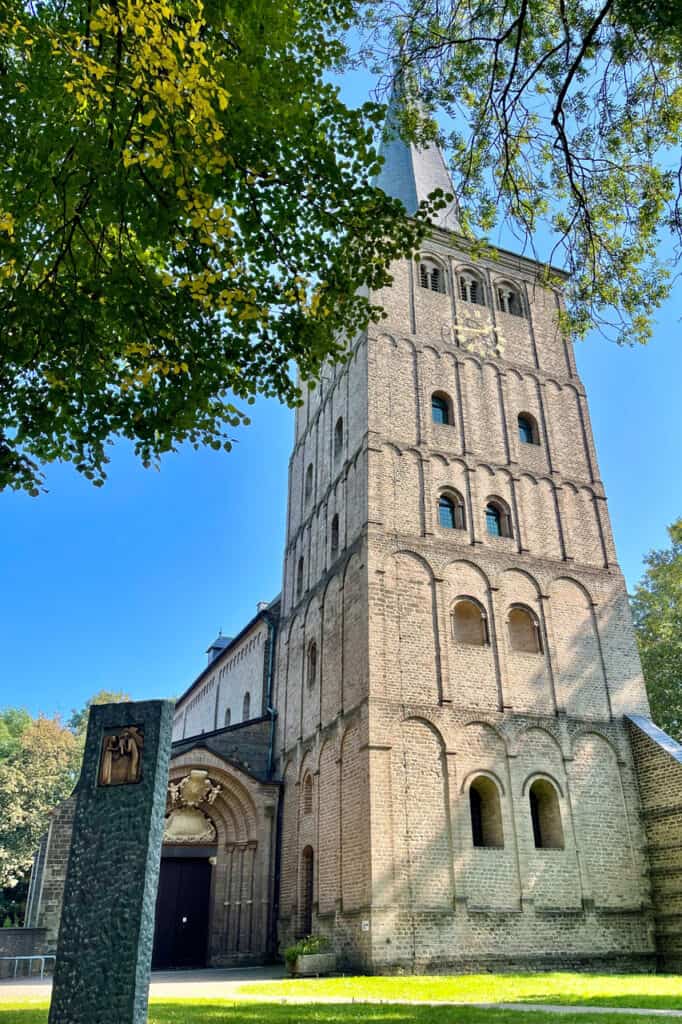 Middeleeuwse kerk op 't Gelders Eiland met groene bomen en blauwe lucht.