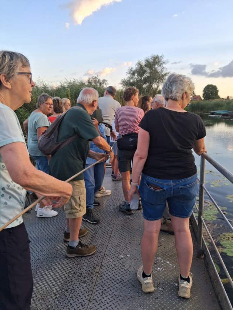 Bezoekers kijken naar de natuur op 't Gelders Eiland tijdens zonsondergang.