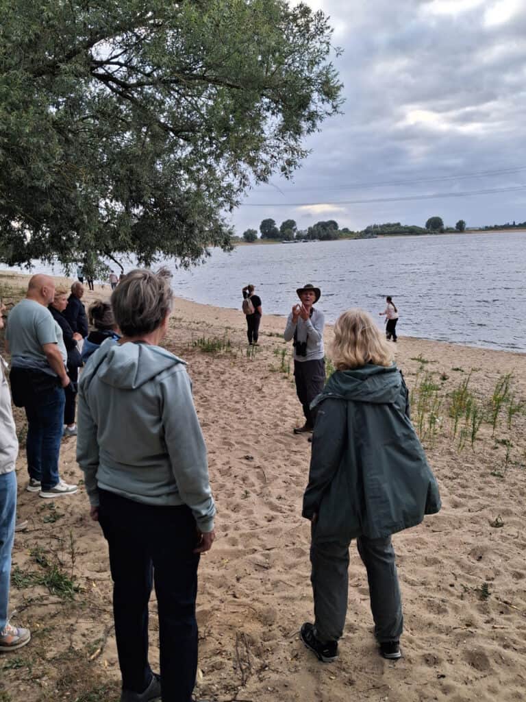 Groep mensen bij rivier op 't Gelders Eiland tijdens zwoele zomeravond.