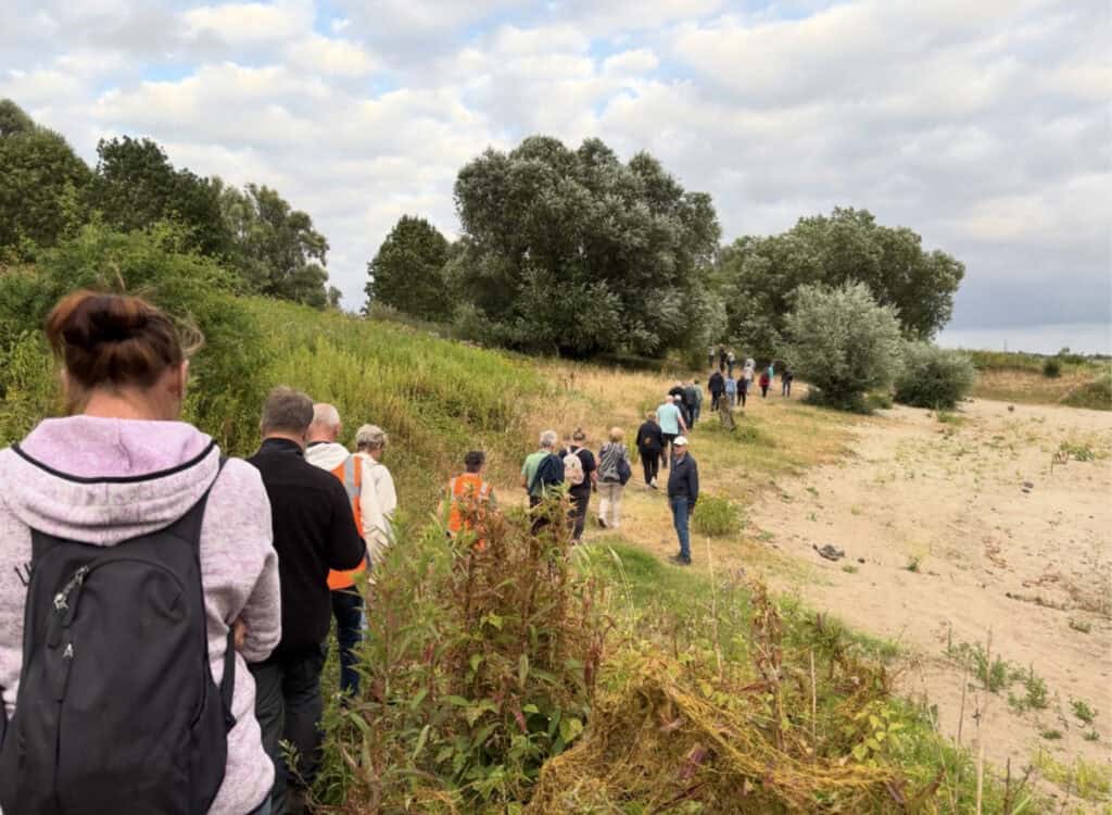 Groep wandelaars op 't Gelders Eiland langs de rivier en natuur.