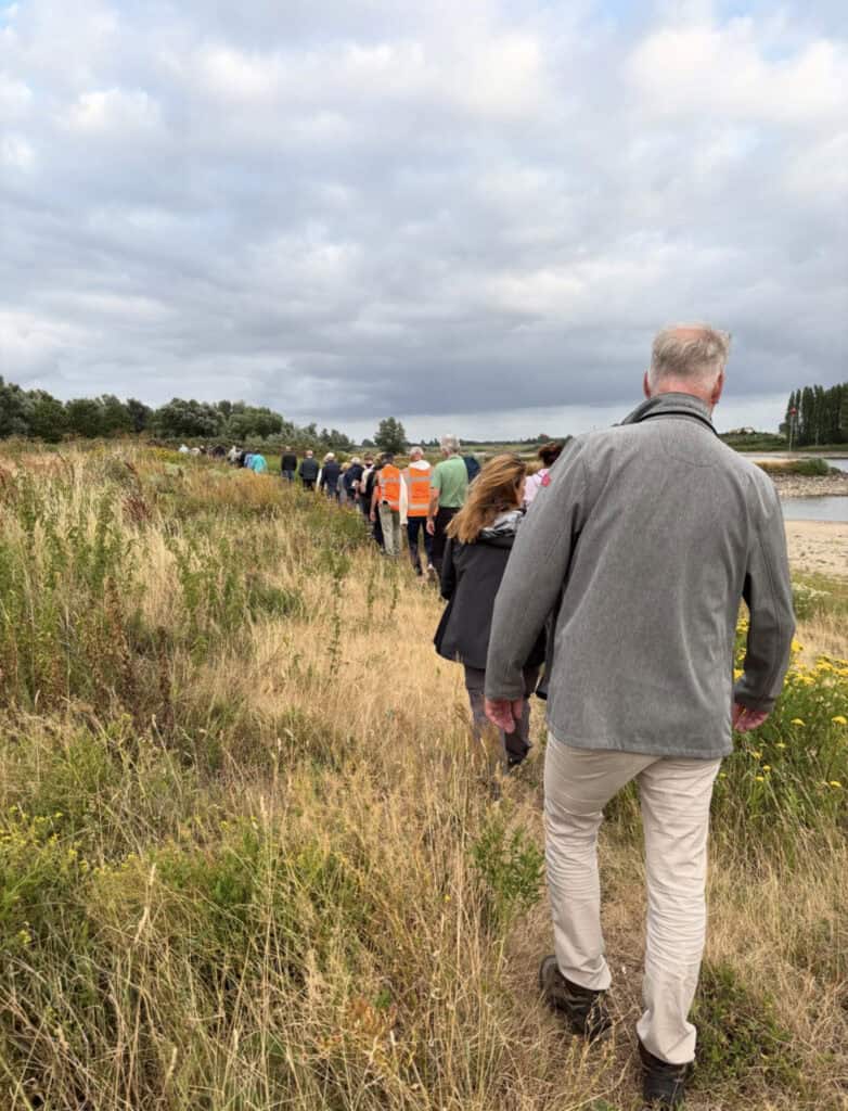 Groep wandelaars langs de rivier op 't Gelders Eiland.