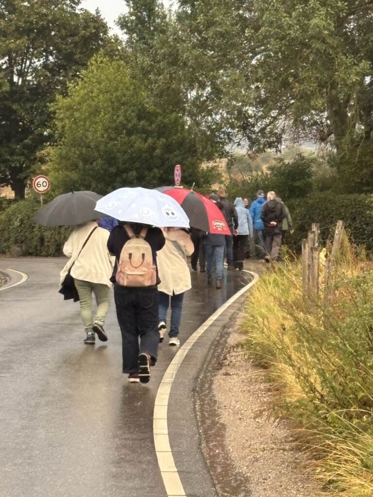 Touristen wandelen met paraplu's op 't Gelders Eiland in regenachtig weer.