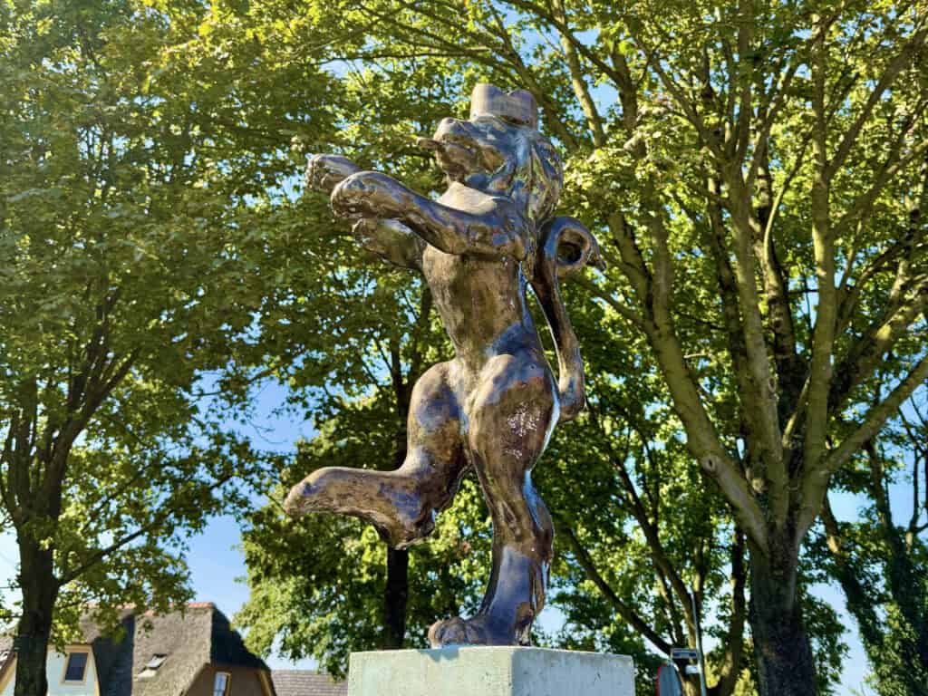 Bronzen beeld op 't Gelders Eiland met groene bomen op de achtergrond.
